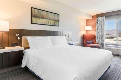 a hotel room with a large white bed and a chair at Hilton Garden Inn Reno in Reno