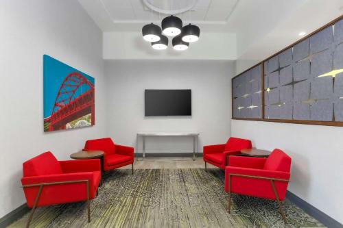 a waiting room with red chairs and a tv at Hampton Inn & Suites Pittsburgh Downtown in Pittsburgh