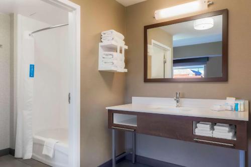 a bathroom with a sink and a mirror and a tub at Hampton Inn & Suites Pittsburgh Downtown in Pittsburgh