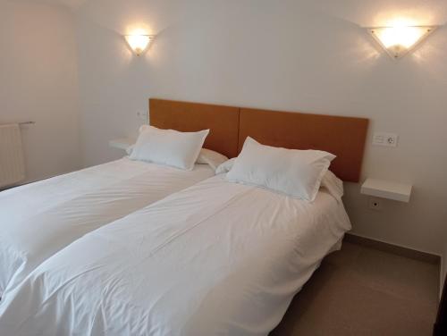 a large white bed with two pillows on it at El Chisco in San Cosme