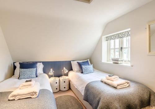 a bedroom with two beds with towels on them at Wisteria Cottage in Snape