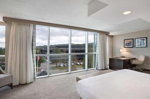 Cette chambre comprend un lit et une grande fenêtre. dans l'établissement Embassy Suites by Hilton Seattle Bellevue, à Bellevue