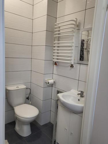 a white bathroom with a toilet and a sink at Pokój gościnny in Żyrardów