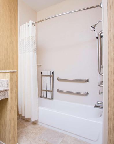 a bathroom with a shower with a white shower curtain at Hampton Inn Shawnee in Shawnee