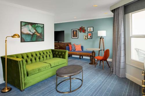 ein Wohnzimmer mit einem grünen Sofa und einem Tisch in der Unterkunft Hayes Mansion San Jose, Curio Collection by Hilton in San Jose