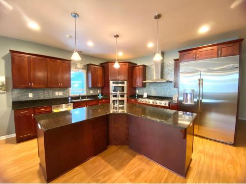 uma cozinha com armários de madeira e um frigorífico de aço inoxidável em Your Dream Home em Milwaukee