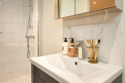 a bathroom with a white sink and a shower at Be London - The St John's Wood Residences in London
