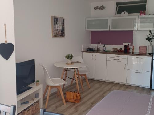 Il comprend une cuisine avec des placards blancs, une table et une télévision. dans l'établissement Les Embiez, à Six-Fours-les-Plages