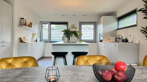 a kitchen with a table with a bowl of fruit on it at VILLA ARYVE in See-, Strand- und Golfplatznähe inklusive NETFLIX, Bad en Suite und Wohlfühlgarantie in Dirkshorn
