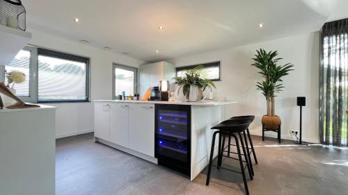 a kitchen with white cabinets and a bar with a stool at VILLA ARYVE in See-, Strand- und Golfplatznähe inklusive NETFLIX, Bad en Suite und Wohlfühlgarantie in Dirkshorn