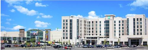 um grande edifício branco com carros estacionados num parque de estacionamento em Embassy Suites By Hilton Syracuse Destiny USA em Syracuse