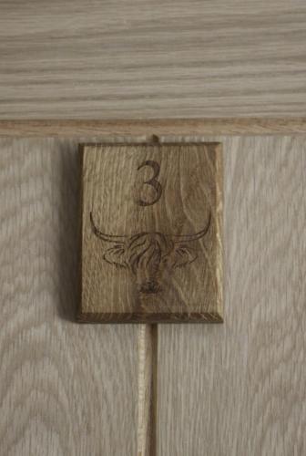 a wooden sign with the number three on a table at The Moo-tel at Moody Meadows in Aberaeron