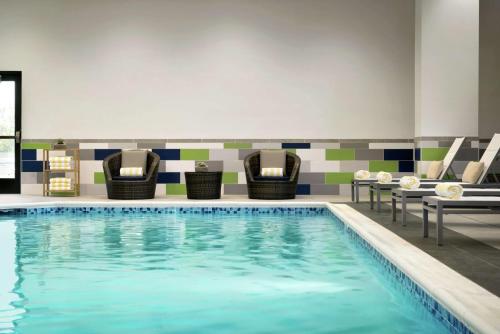 een zwembad in een hotelkamer met stoelen bij Embassy Suites By Hilton Syracuse Destiny USA in Syracuse