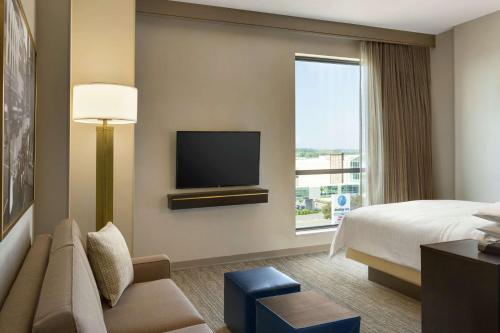 a hotel room with a bed and a tv at Embassy Suites By Hilton Syracuse Destiny USA in Syracuse
