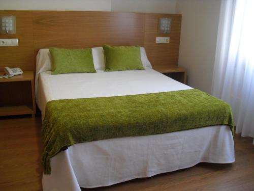 a bedroom with a large bed with a green blanket at Hotel Brisa del Mar in O Grove