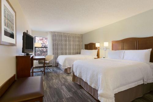 una camera d'albergo con due letti e una televisione di Hampton Inn Zanesville a Zanesville