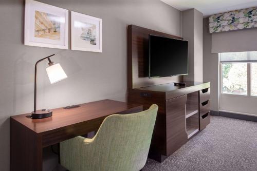 a room with a desk with a television and a chair at Hampton Inn & Suites Arlington Crystal City DCA in Arlington