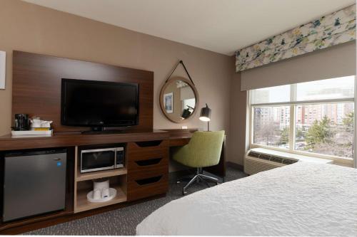 a hotel room with a bed and a television on a desk at Hampton Inn & Suites Arlington Crystal City DCA in Arlington