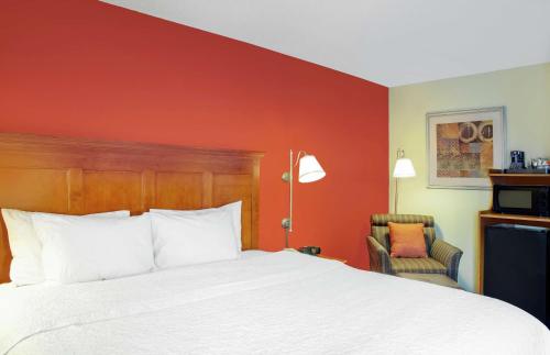 a hotel room with a bed and a red wall at Hampton Inn Merrillville in Merrillville