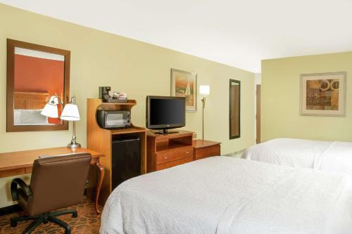 a hotel room with two beds and a desk with a television at Hampton Inn Merrillville in Merrillville