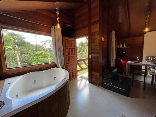 a bathroom with a bath tub in a room with a window at Sítio Balango: Seu refúgio em Domingos Martins. Chalés para casais e casa para grupo de pessoas in Domingos Martins