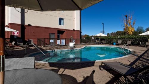 einen Pool auf einer Terrasse mit Stühlen und einem Sonnenschirm in der Unterkunft Hampton Inn Statesville in Statesville