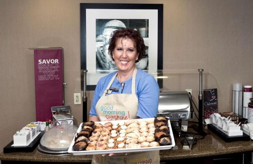 a woman standing behind a counter with a tray of pastries at Hampton Inn Statesville in Statesville