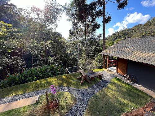 a small yard with a bench in the grass at Sítio Balango: Seu refúgio em Domingos Martins. Chalés para casais e casa para grupo de pessoas in Domingos Martins