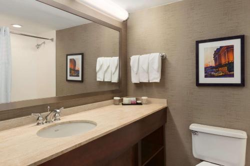 a bathroom with a sink and a mirror and a toilet at Embassy Suites by Hilton Baltimore at BWI Airport in Linthicum Heights
