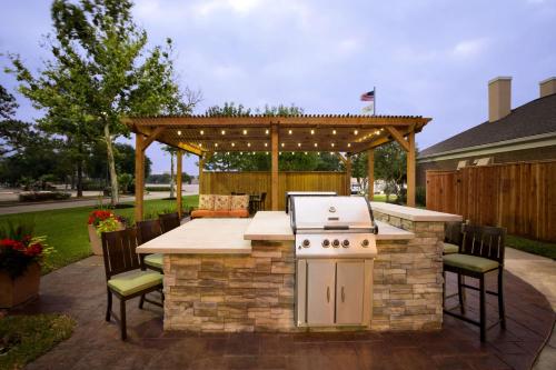 an outdoor kitchen with a grill and a table and chairs at Homewood Suites by Hilton Houston-Willowbrook Mall in Houston