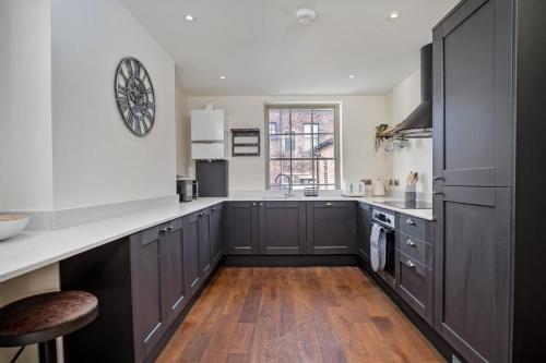 a kitchen with gray cabinets and a wooden floor at Paradise Square-Remodelled 18th Century Apartment in Sheffield