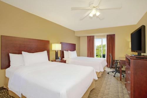 a hotel room with two beds and a flat screen tv at Homewood Suites by Hilton Tampa-Brandon in Tampa