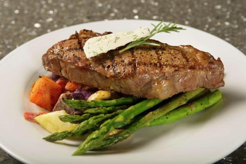 a plate of food with a piece of meat and vegetables at Hilton Garden Inn College Station in College Station
