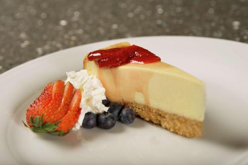 a piece of cheesecake and a strawberry and blueberries on a plate at Hilton Garden Inn College Station in College Station