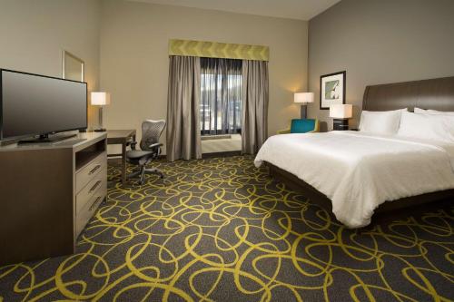 ein Hotelzimmer mit einem Bett und einem Flachbild-TV in der Unterkunft Hilton Garden Inn College Station in College Station