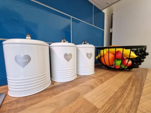 quattro tazze bianche su un bancone con un cesto di frutta di Charming Accommodation Steps from Downtown a Liverpool