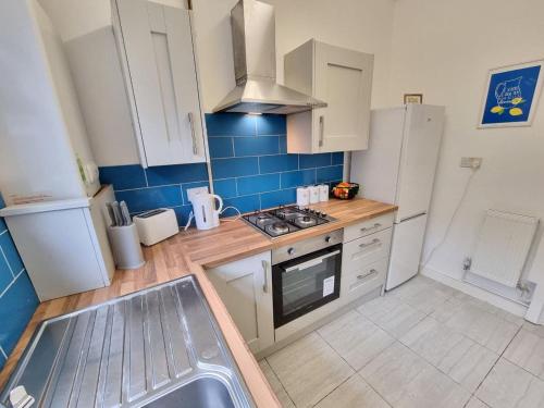 una cucina con armadi bianchi e piastrelle blu di Charming Accommodation Steps from Downtown a Liverpool
