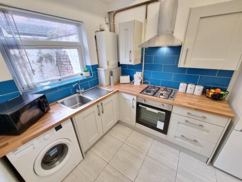 a kitchen with a sink and a washing machine at Charming Accommodation Steps from Downtown in Liverpool