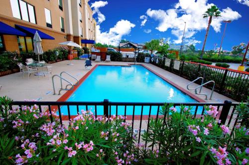 a swimming pool in front of a building with flowers at Hampton Inn & Suites Tomball in Tomball
