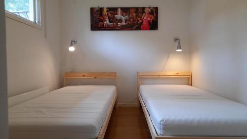 two beds in a room with a picture on the wall at Alholmens Camping & Stugby in Sölvesborg
