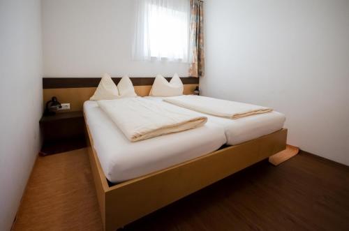 a bedroom with a bed with white sheets and a window at Familienhotel Steindl in Millstatt