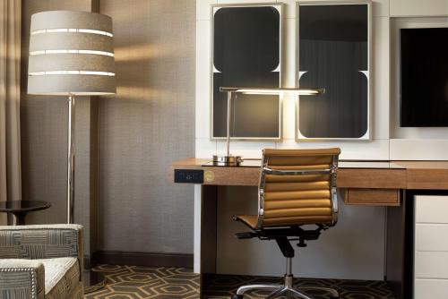 a desk with a chair and a lamp in a room at DoubleTree by Hilton Hotel Dallas Campbell Centre in Dallas