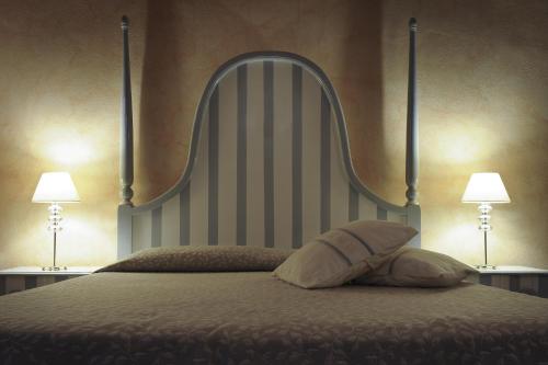a bed with a large headboard and two lamps at Antica Locanda Lunetta in Màndas
