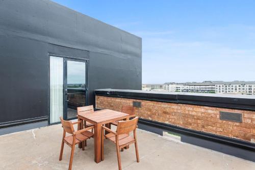 a wooden table and two chairs on a balcony at NYLO Dallas Plano Hotel, Tapestry Collection by Hilton in Plano