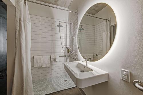 a white bathroom with a sink and a mirror at NYLO Dallas Plano Hotel, Tapestry Collection by Hilton in Plano