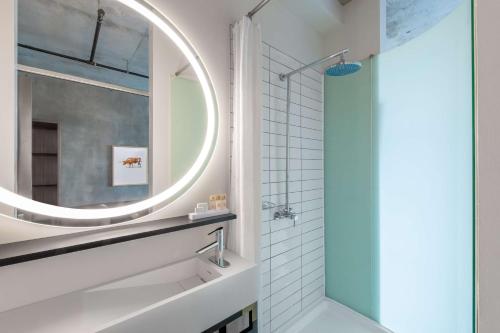 a bathroom with a large mirror and a shower at NYLO Dallas Plano Hotel, Tapestry Collection by Hilton in Plano