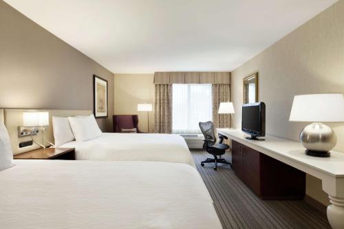 a hotel room with two beds and a television at Hilton Garden Inn Gilroy in Gilroy