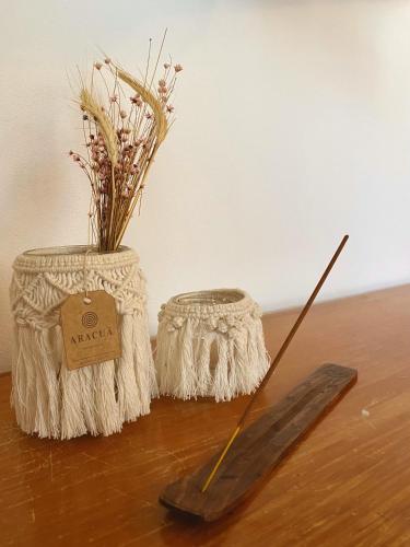 a wooden table with two vases and a wooden stick at Haleakala Hostel & Pousada in Praia do Rosa