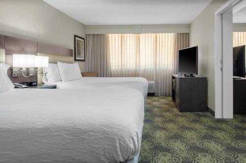 a hotel room with two beds and a flat screen tv at Hilton Garden Inn Reagan National Airport in Arlington