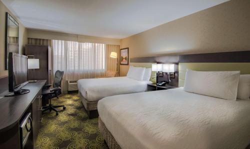 a hotel room with two beds and a flat screen tv at Hilton Garden Inn Reagan National Airport in Arlington
